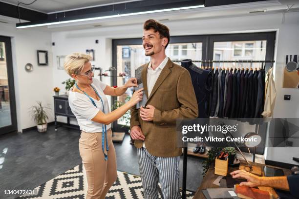 店内のスーツ用の販売員とクライアントピッキングテキスタイル - tailor made ストックフォトと画像