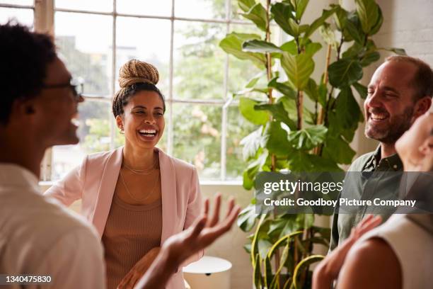 diverse group of businesspeople laughing together while standing in an office - corporate modern office bright diverse imagens e fotografias de stock