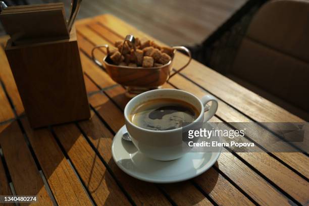small business re-opening. cup of coffee and brown sugar chunks at the wooden table of local outdoor cafe - americano photos et images de collection