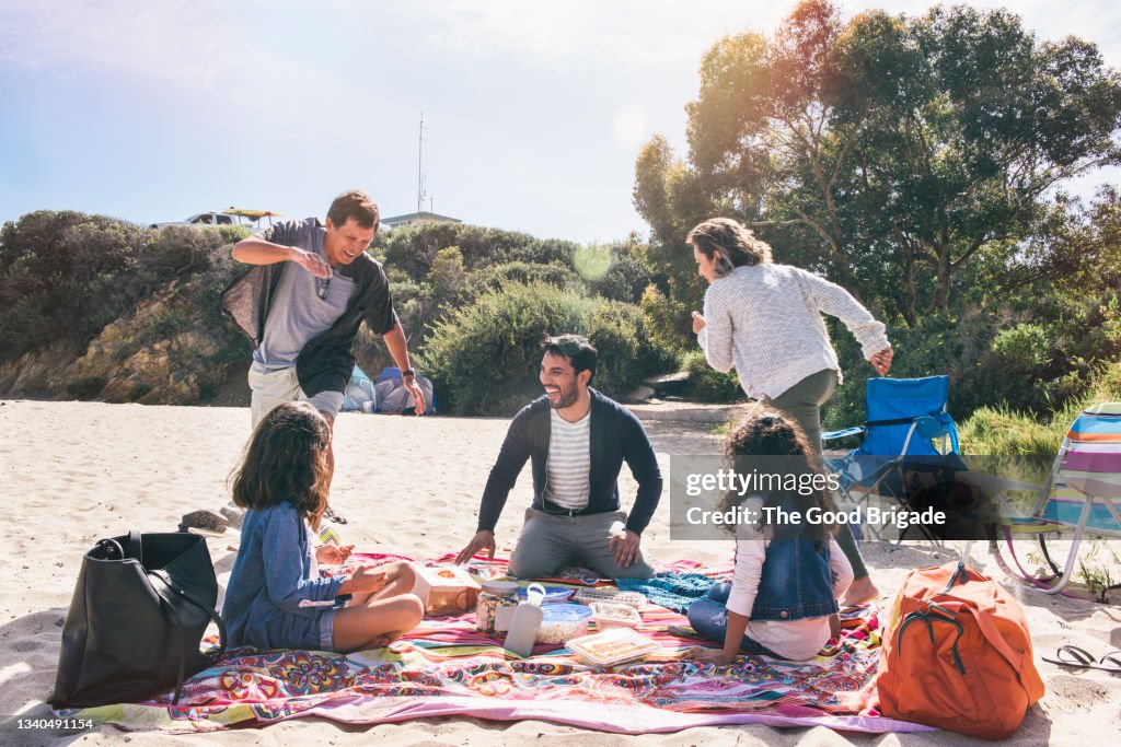 Family playing chase at beach during vacation