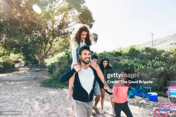 smiling father carrying daughter on shoulders while walking at beach - latin american and hispanic stock pictures, royalty-free photos & images