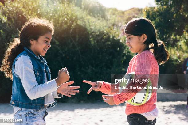 smiling siblings playing a rock paper scissors at beach on sunny day - scissors paper stone stock pictures, royalty-free photos & images