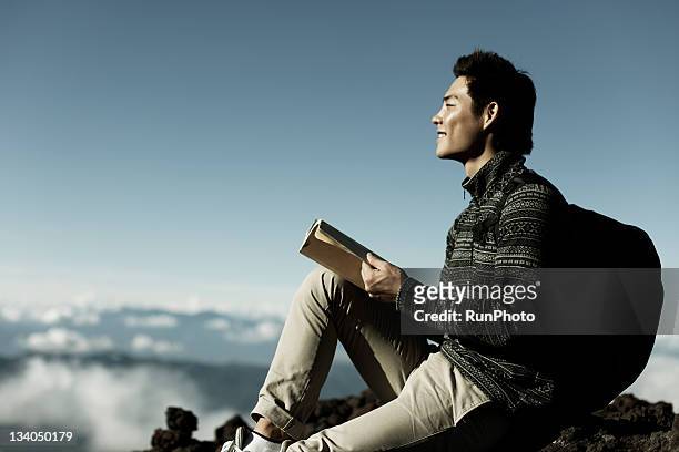 young man reading a book in the mountain - travel with book stock pictures, royalty-free photos & images