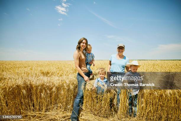 wide shot portrait of grandmother daughter and grandsons standing in wheat field on farm - fundo azul fotografías e imágenes de stock