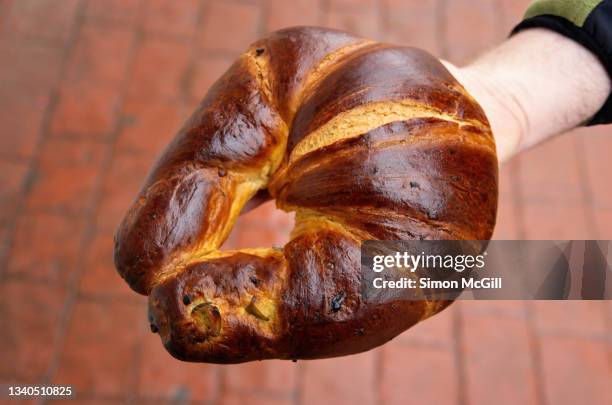 man's hand holding a traditional pan de higo (fig croissant) from a street stall - chignahuapan stock pictures, royalty-free photos & images