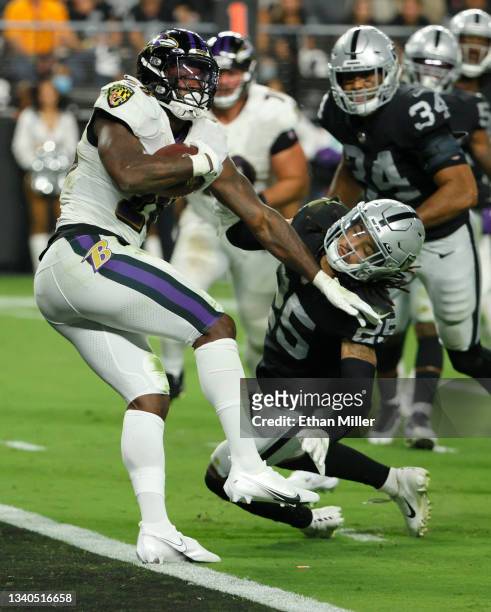 Latavius Murray of the Baltimore Ravens avoids a tackle by safety Trevon Moehrig of the Las Vegas Raiders to score on an 8-yard touchdown run during...