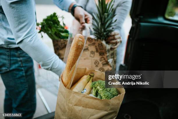 young couple is packing groceries in car trunk - pregnant woman car stock pictures, royalty-free photos & images