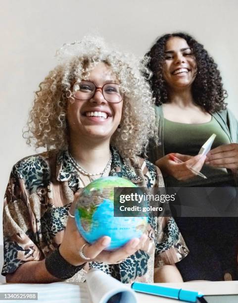 junge lächelnde frau, die globus in der hand hält - to assemble world stock-fotos und bilder