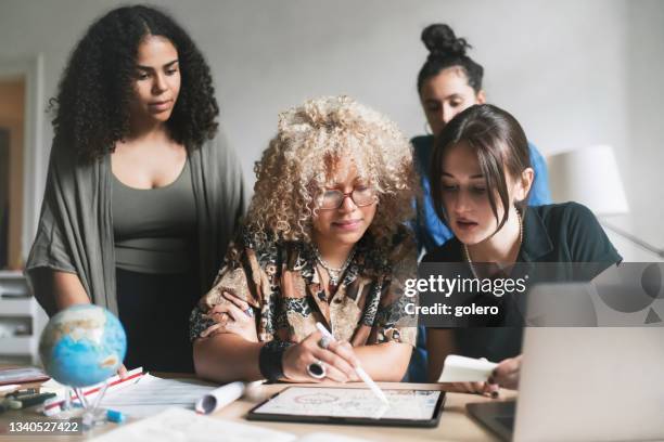 four young woman analyzing together climate concepts on tablet - global fashion collective stock pictures, royalty-free photos & images