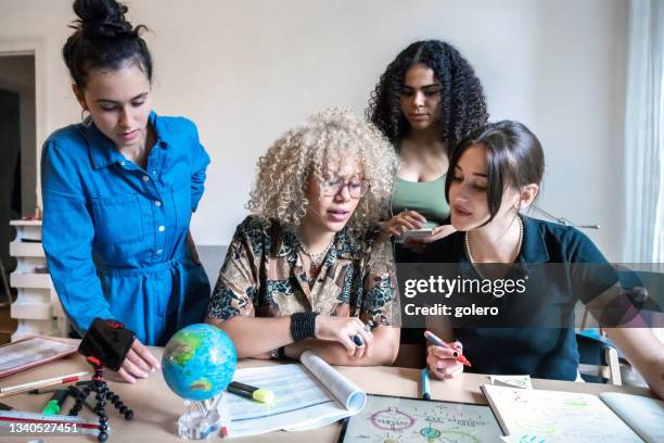 vier junge frauen arbeiten gemeinsam an präsentation für klimaschutz am schreibtisch - global fashion collective stock-fotos und bilder