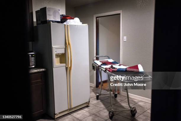 Stretcher waits in a kitchen as a funeral home worker prepares to transport the body of a woman who died of Covid-19 in her bed at home on September...