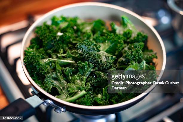cooking sautéed kale with garlic and olive oil - kale bunch stock pictures, royalty-free photos & images