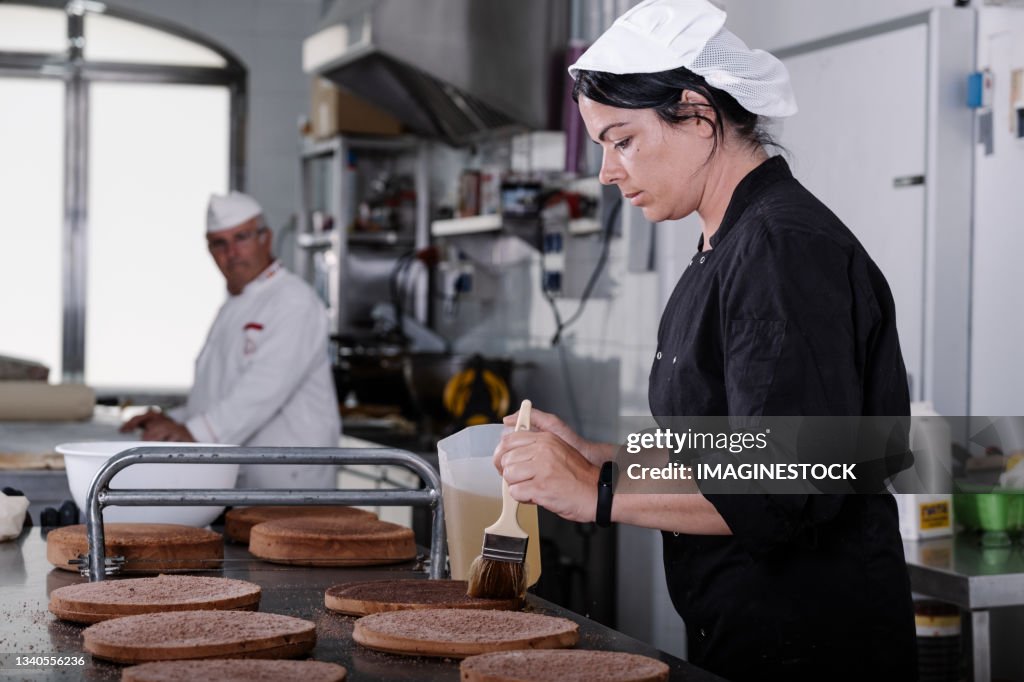 Young woman pastry chef making cakes in the workshop