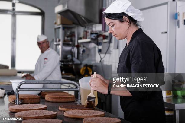 young woman pastry chef making cakes in the workshop - pâtissier photos et images de collection
