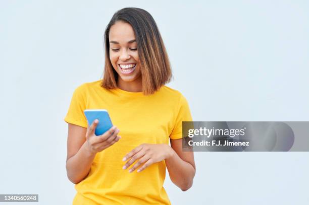 woman using mobile phone in front of white wall - one young woman only texting foto e immagini stock