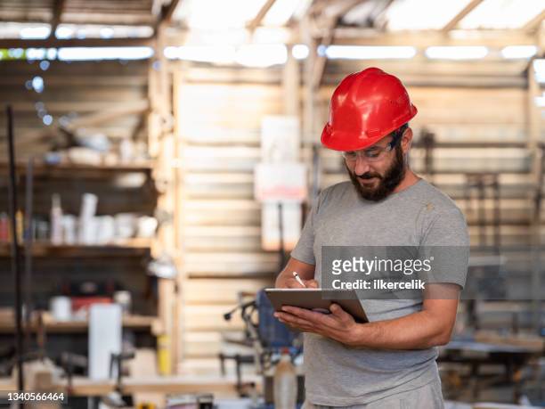 carpenter working in his workshop using digital tablet - contract manufacturing stock pictures, royalty-free photos & images