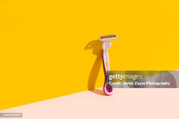 pink razor blade on yellow/pink background - razor blade stockfoto's en -beelden