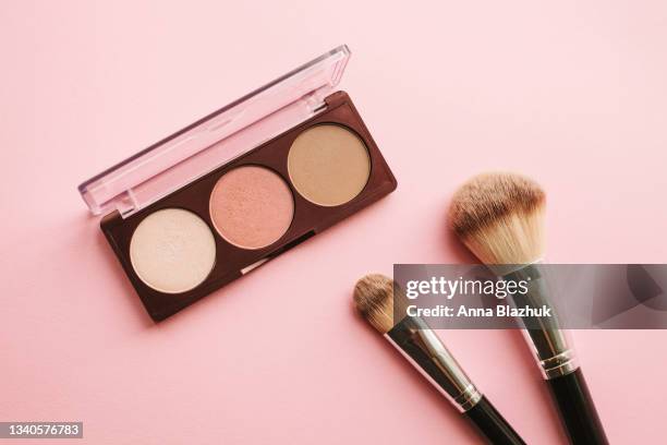 face powder, blusher and highlighter palette of nude colors over pink background - make up brush stock-fotos und bilder
