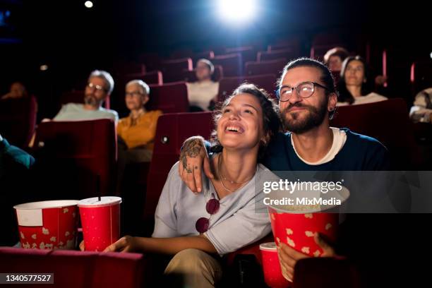 young couple enjoying a fun movie at the cinema - film premiere stock pictures, royalty-free photos & images