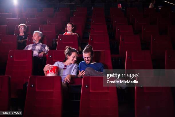 young couple on the movies using smartphone - smartphone video stock pictures, royalty-free photos & images