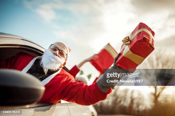 young santa claus driving a car and having a fun with his female friend - christmas driving stock pictures, royalty-free photos & images