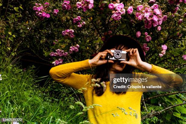 adult woman taking a picture with an analog camera in the garden - photography themes stock pictures, royalty-free photos & images