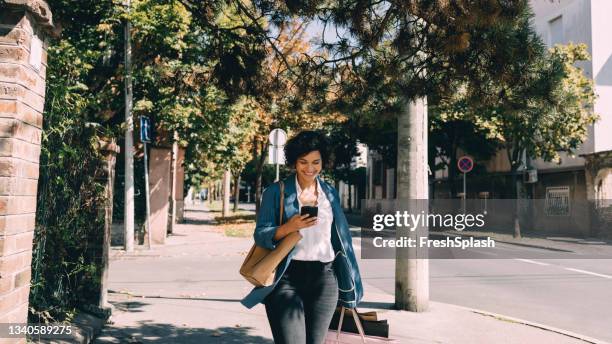 beautiful woman using mobile phone in city - woman walks down street stock pictures, royalty-free photos & images