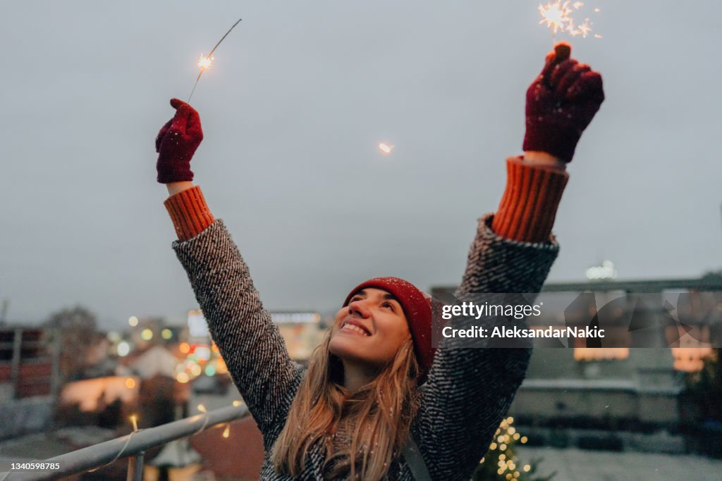Young woman with sparklers on a rooftop terrace