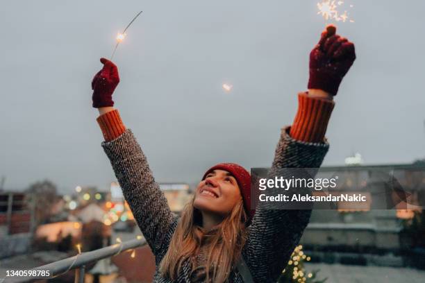 young woman with sparklers on a rooftop terrace - sparkler imagens e fotografias de stock
