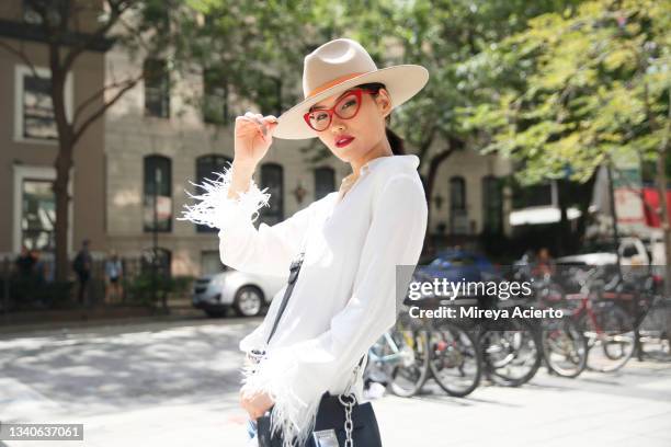 portrait of an asian millennial woman with red reading glasses, in the downtown district of a city, wearing a tan colored hat and a white blouse. - chicago lifestyle stock pictures, royalty-free photos & images