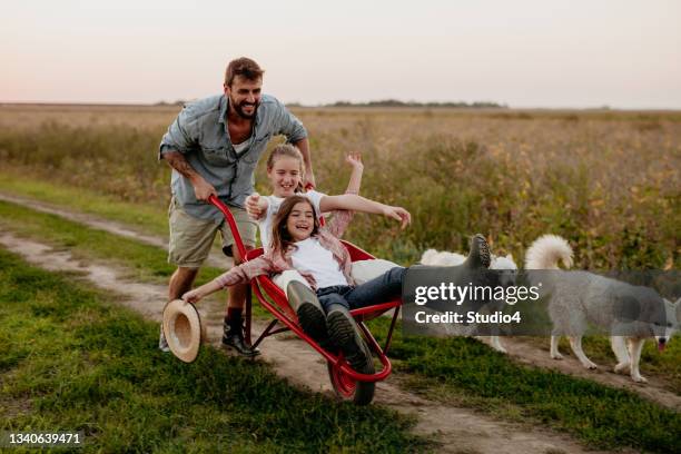 farmer enjoying with his girls - wheelbarrow stock pictures, royalty-free photos & images