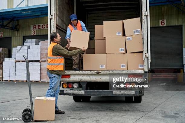 black female truck driver loading boxes in cargo space - vrachtwagen stockfoto's en -beelden