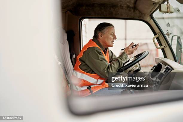 male trucker in early 60s using phone in cab - truck driver 個照片及圖片檔