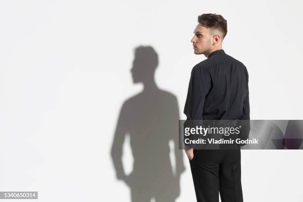 portrait man and shadow at white wall - three quarter length stock pictures, royalty-free photos & images