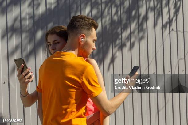 couple hugging and using smart phones - couple smartphone stockfoto's en -beelden
