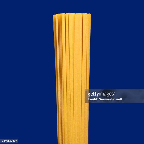close up uncooked spaghetti pasta on blue background - spaghetti foto e immagini stock