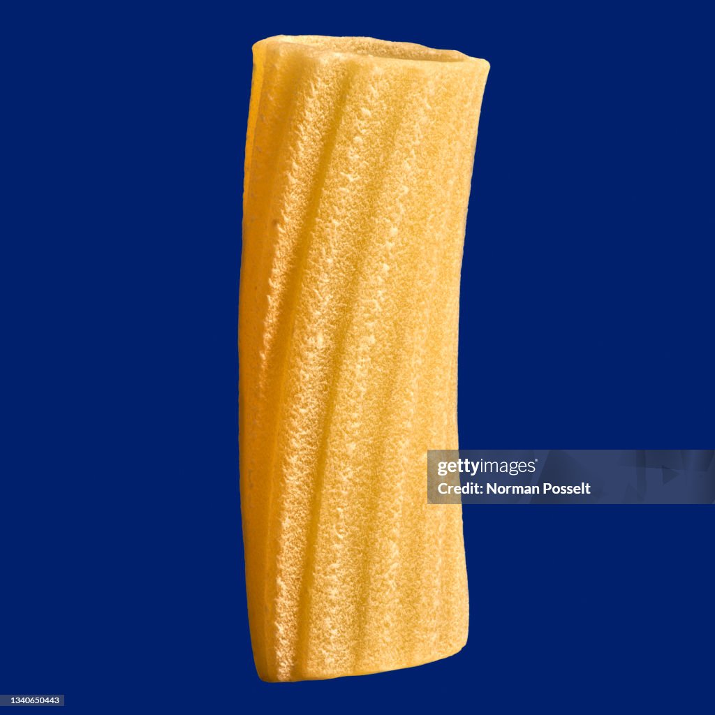 Close up uncooked penne rigate noodle on blue background