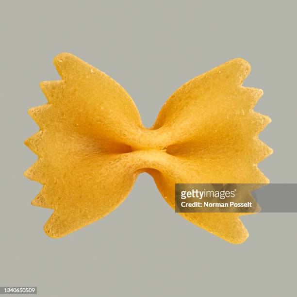 close up uncooked farfalle bowtie pasta on gray background - farfalle stock-fotos und bilder
