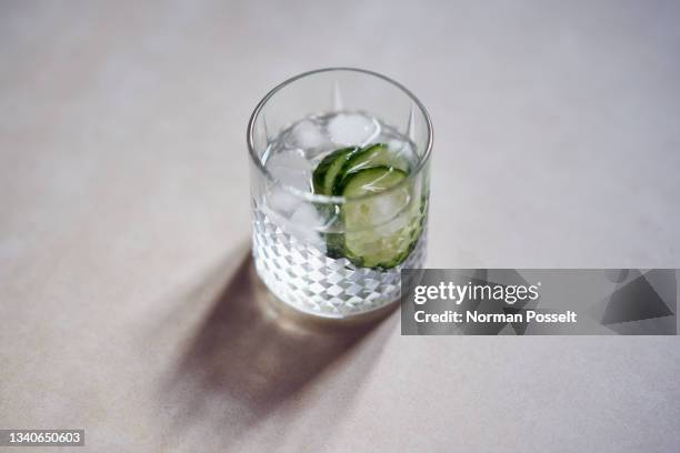 glass of ice water with cucumber slices - cucumber cocktail stock pictures, royalty-free photos & images