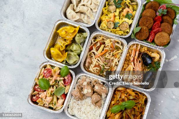 food delivery. сhinese takeaway food, italian food delivery. different aluminium lunch box with dumplings, noodles with chicken, rice with chicken, pasta with salmon, falafel - cibo precotto foto e immagini stock