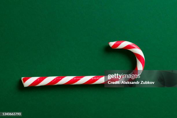 christmas striped red and white candy, on a beautiful green holiday background. the concept of a happy christmas. copy the space. - christmas bauble isolated stock-fotos und bilder