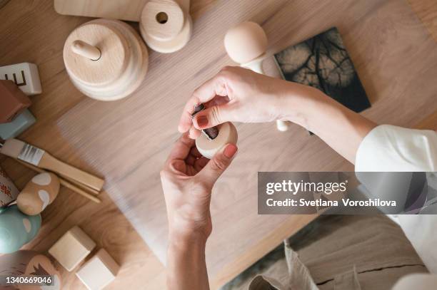 hands of master in a linen apron polishing a wooden rattle in her workshop. the process of handcrafting children's toys from wood. - diy craft stock pictures, royalty-free photos & images