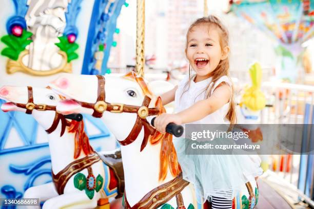 bel bambino sul cavallo carosello. la ragazza carina sta cavalcando l'attrazione. celebrazione divertente - carousel foto e immagini stock