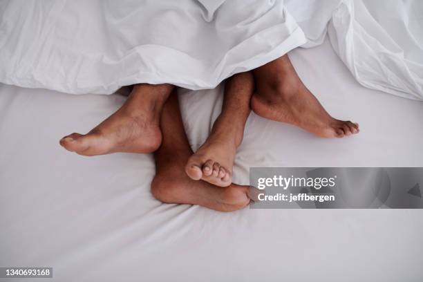 abgeschnittene aufnahme eines nicht wiederzuerkennbaren paares, das in den frühen morgenstunden zu hause zusammen im bett liegt - feet in bed stock-fotos und bilder