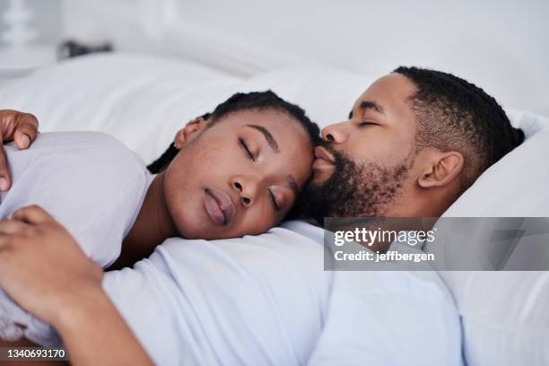 shot of a young couple cuddling while sleeping in bed together at home - black man sleeping in bed stock pictures, royalty-free photos & images