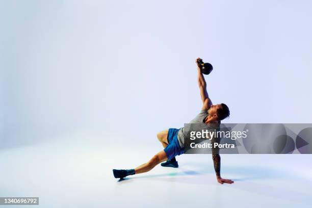 starker junger mann trainiert mit kettle bell - mann gewichtheben stock-fotos und bilder