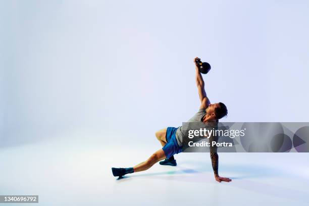 strong young man exercising with kettle bell - roupa desportiva imagens e fotografias de stock