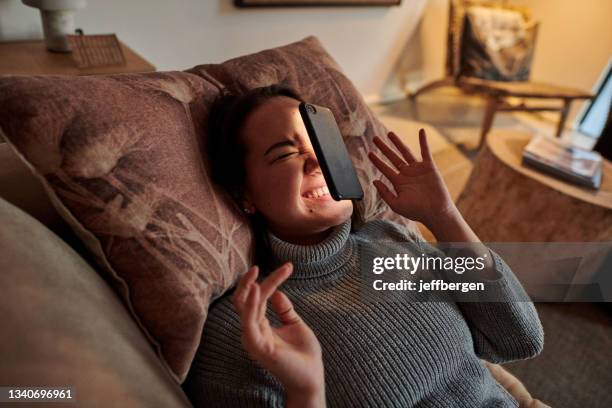 photo d’une jeune femme allongée sur le canapé après que son téléphone lui soit tombé sur le visage - meme face photos et images de collection