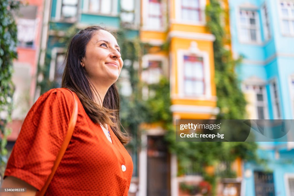 Portrait of beautiful woman in front of colorful buildings in city