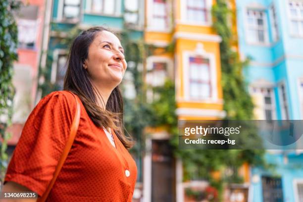 retrato de linda mulher em frente a prédios coloridos na cidade - multi colored dress - fotografias e filmes do acervo